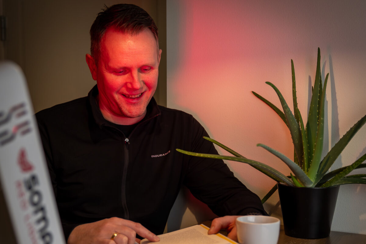 Mann leser bok i rødt lys terapi og rødlysterapi